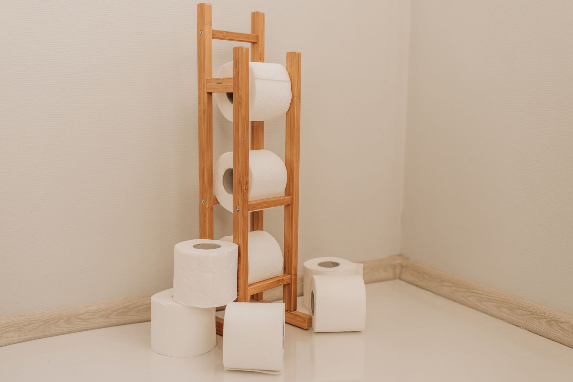 Neatly stacked toilet paper rolls on a bamboo rack in a minimalist bathroom corner. (Photo by Vlada Karpovich on Pexels)